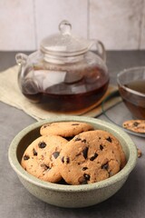 Delicious chocolate chip cookies and tea on grey table