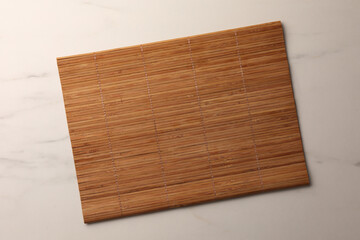 Bamboo mat on white marble table, top view. Space for text