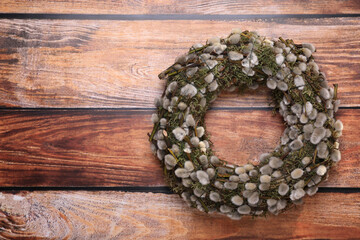 Wreath made of beautiful willow flowers on wooden table, top view. Space for text