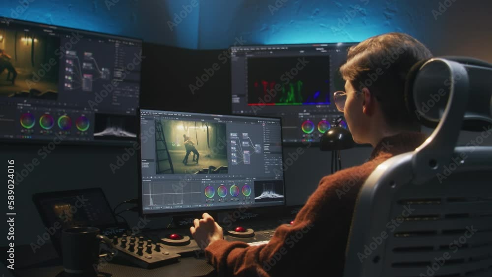 Aufkleber the editor works in studio on computer, uses color grading control panel, edits video, makes color c