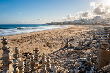 Stone balancing arrangements of stacked stones on Praia da Luz beach, created in a meditative...