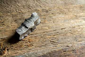 Shard of an artillery shell. Fragment of an artillery bomb on a background of rough wood.