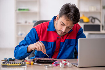 Young male repairman repairing computer
