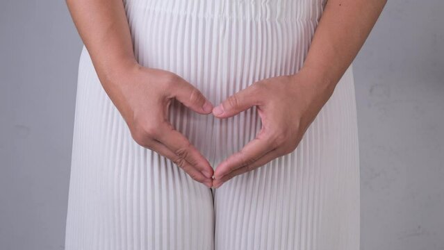 Woman holding heart shape hands on her crotch isolated on white background. Gynecological and Health hygiene concept.