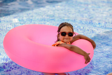 Little girl kid, is swimming with an inflatable circle in the swimming pool.