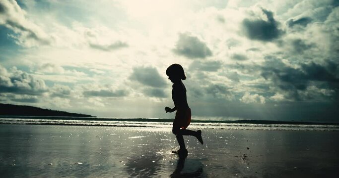 Silhouette of boy run on beach in slow motion. Concept of freedom, happy memorie