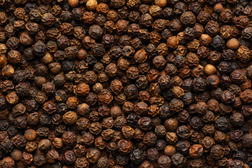 Black pepper grains as background close up.