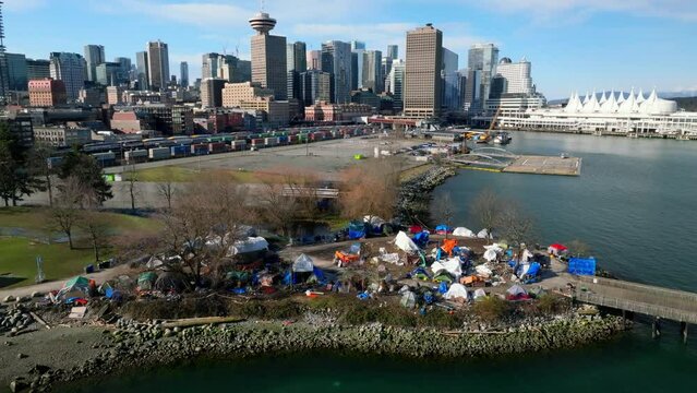 Homeless Tents At CRAB Park Overlooking The Downtown Vancouver Skyline In BC, Canada. - aerial pullback