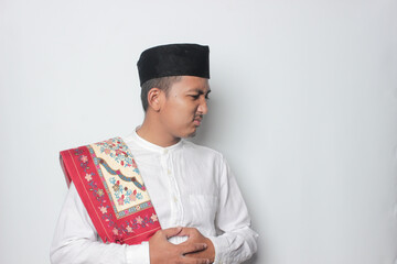 An Asian Muslim man feels so hungry because of the hot weather during the summer season while...