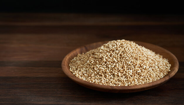 sesame seed in wood plate on wooden table background. a pile of  Toast sesame seeds. sesame seed. pile of sesame seed in wood plate 