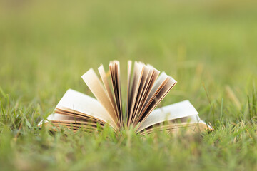 Open book on green grass in a field background concept for reading, relaxing and recreation