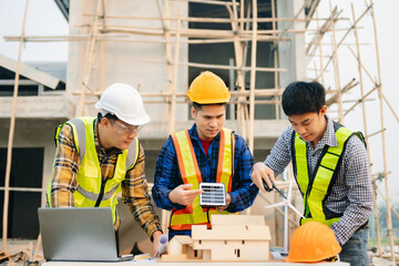 Engineers are discussing data working and laptop or tablet with architectural project at new construction site on big project. in sun light.