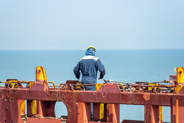 Seaman working on deck of the container vessel. He is preparing ship to enter shipyard.