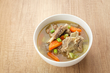 Sop Iga (Beef ribs soup) made from ribs, carrots, leeks.  Served in white bowl. Indonesian food
