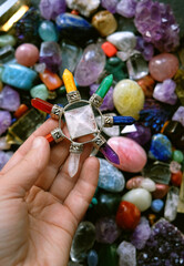 Quartz Pyramid energy generator in hand on abstract blurred background of colorful gemstones....