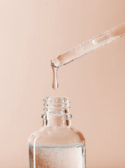 serum pipette close-up with falling drop on a beige background