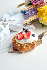 French pastry with white sweet cream, almonds, strawberries. Sweet bun on a marble background