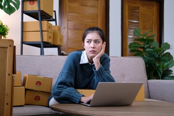 Portrait of an Asian woman's business owner is stressing and un comfortable surrounded by boxes....