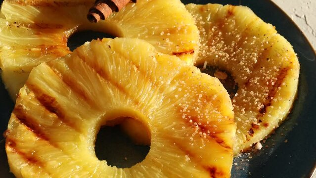 grilled pineapple slices sprinkle cinnamon in a plate. The sun's rays on the photo.