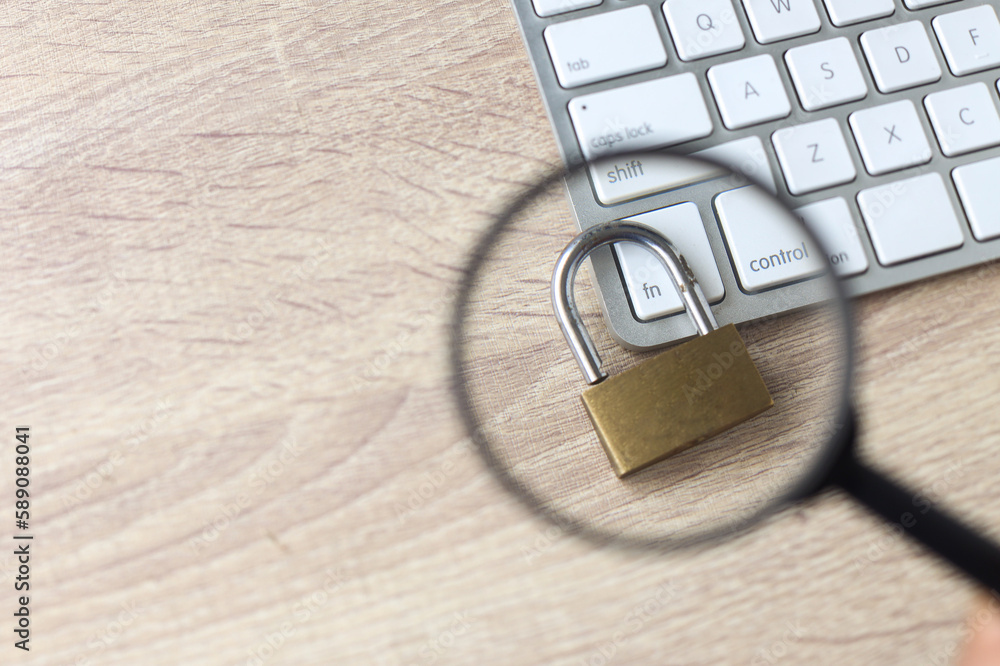 Poster selctive focus magnifying glass and padlock on keyboard at office table. cyber security concept. enc