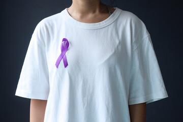 Cropped shot of woman wearing white t shirt and purple ribbon on dark grey background, closeup....
