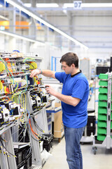 young apprentice assembles components and cables in a factory in a switch cabinet - workplace industry with future