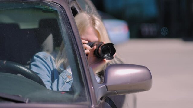 Woman with camera sits inside car and takes photo with professional camera, private detective or paparazzi spy. Journalist seeks synsation and follows celebrities.