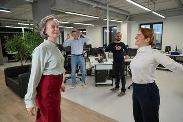 Fototapeta na wymiar Four office workers warm up during a break. Employees do fitness exercises at the workplace. 