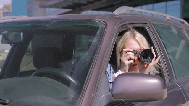 Woman with camera sits inside car and takes photo with professional camera, private detective or paparazzi spy. Journalist seeks synsation and follows celebrities.