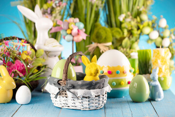 Fototapeta na wymiar Easter theme. Easter decorations. Easter eggs in basket and easter bunny. Bouquet of spring flowers. Blue background.