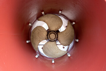 View on the stern thruster propeller of the big container ship. Ship is in the dry dock for scheduled maintenance and painting.