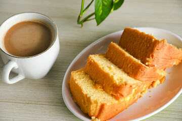 pieces of sponge cake or kue bolu served on a plate with a glass of coffee