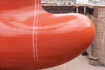 Close up view on the newly red painted bulbous bow of the big container ship. She is inside dry...