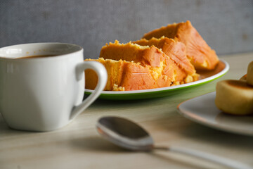 pieces of sponge cake or kue bolu served on a plate with a glass of coffee