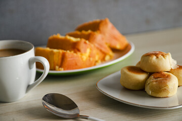 pieces of sponge cake or kue bolu served on a plate with a glass of coffee