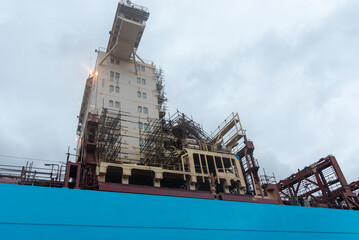 Cargo ship in a dry dock, view on the superstructure under maintenance. 