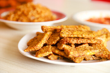 Tempe goreng or fried tempeh is served on a plate along with sambal