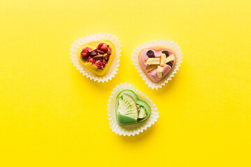 chocolate sweets in the form of a heart with fruits and nuts on a colored background. top view with space for text, holiday concept