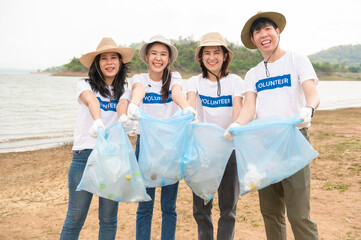 Volunteers from the Asian youth community using rubbish bags cleaning  up nature par