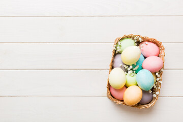 Happy Easter composition. Easter eggs in basket on colored table with gypsophila. Natural dyed colorful eggs background top view with copy space