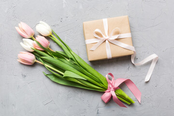 Pink tulips flowers and gift or present box on colored table background. Mothers Day, Birthday, Womens Day, celebration concept. Space for text top view