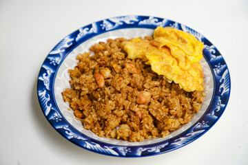 Nasi goreng kecap or soy sauce fried rice topped with scrambled eggs and prawns. Indonesian traditional food