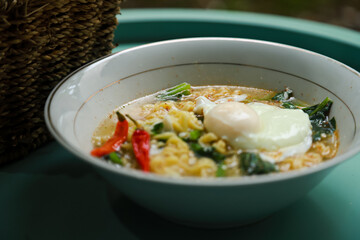 instant noodle soup topped with eggs, vegetables and chilies served in a bowl