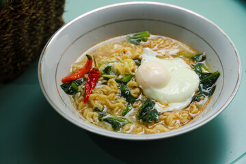 instant noodle soup topped with eggs, vegetables and chilies served in a bowl