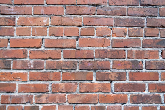 A brick wall, red clay bricks laid in a regular pattern to make a wall.