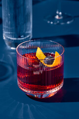 Popular cocktail negroni with gin and vermouth on blue background with shadow. Negroni cocktail on...