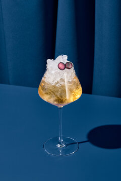Elegant cocktail with martini in contemporary style on colorful background. Vermouth cocktail with ice on blue backdrop in trendy design. Modern concept with alcohol beverage. Bartender cocktail.