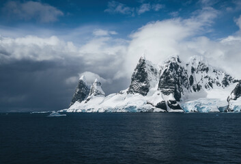 Landscape of snowy mountains and icy shores of the Lemaire Channel in the Antarctic Peninsula, Antarctica. Global warming and climate change concept.