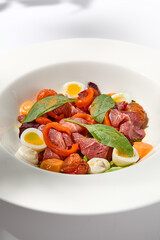 Salad with roast beef, vegetables and eggs on white table with harsh shadows. Steak salad in modern style with shadows of leaves. Flashy food. Meat salad with pastrami in summer menu.
