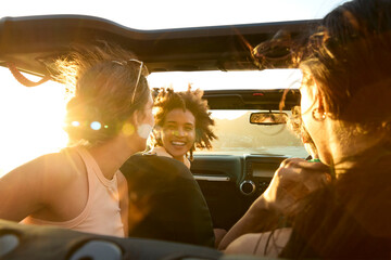 Group Of Laughing Female Friends Having Fun In Open Top Car On Road Trip